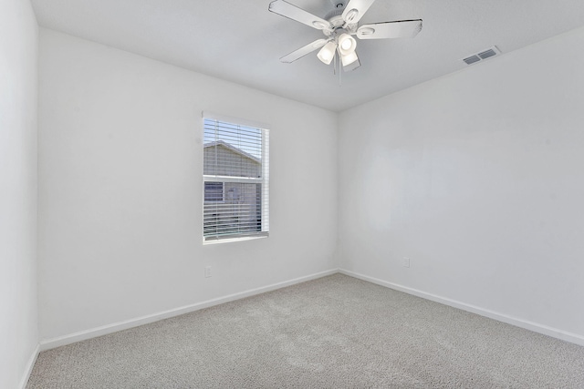 carpeted spare room with a ceiling fan, visible vents, and baseboards