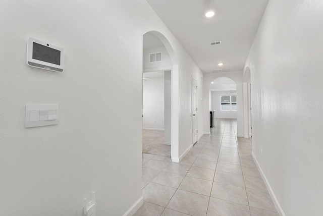 hallway featuring light tile patterned floors, arched walkways, and visible vents