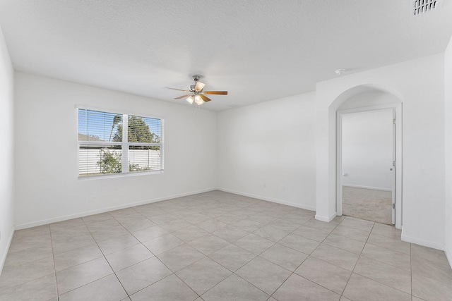 unfurnished room featuring arched walkways, visible vents, baseboards, and ceiling fan