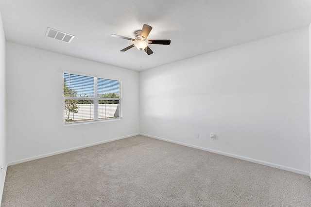 carpeted empty room featuring baseboards, visible vents, and ceiling fan