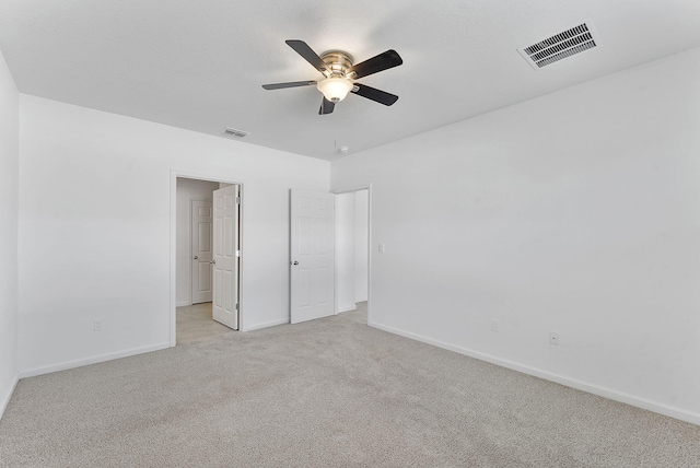 unfurnished bedroom featuring visible vents, light colored carpet, baseboards, and ceiling fan