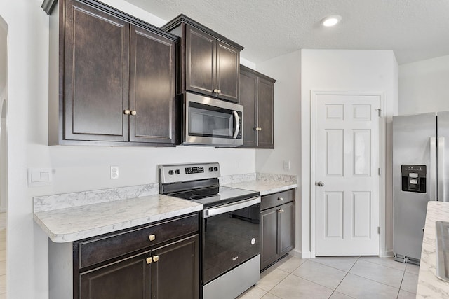 kitchen featuring stainless steel appliances, a textured ceiling, dark brown cabinets, and light countertops