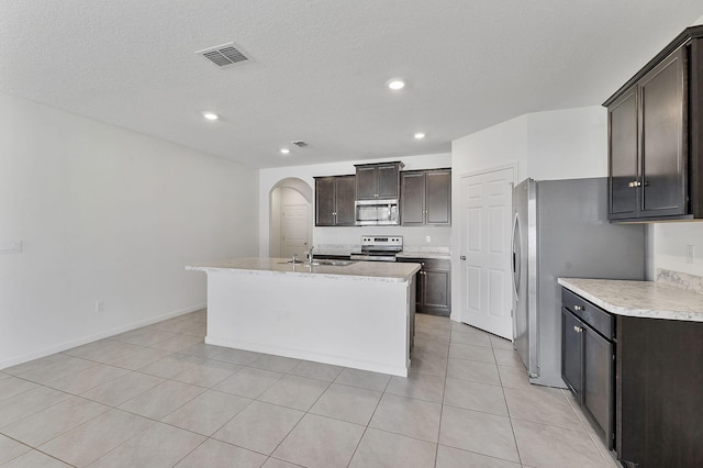 kitchen featuring visible vents, stainless steel appliances, arched walkways, dark brown cabinetry, and light countertops