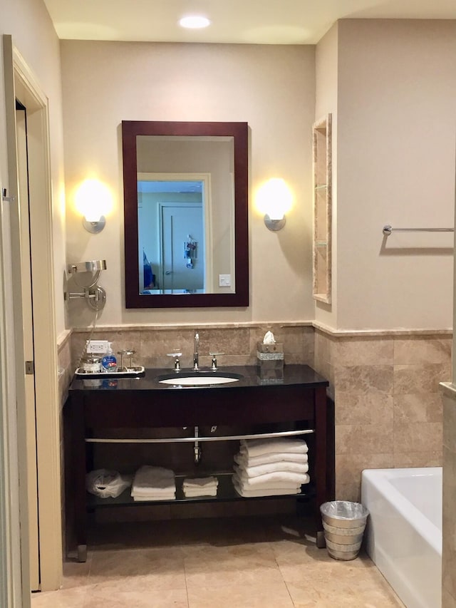 full bathroom featuring vanity, wainscoting, tile walls, a bathtub, and tile patterned floors