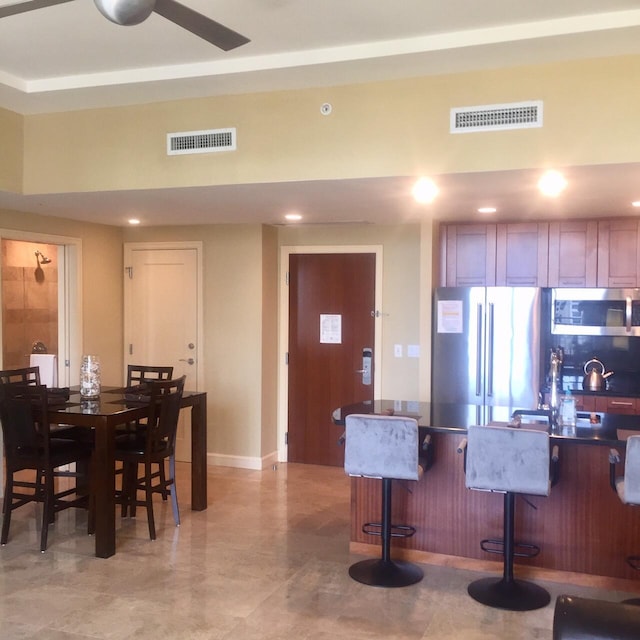 kitchen featuring visible vents, dark countertops, a breakfast bar area, and stainless steel appliances