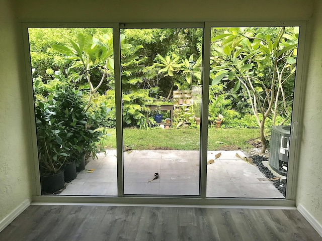 doorway to outside with a healthy amount of sunlight, a textured wall, and wood finished floors