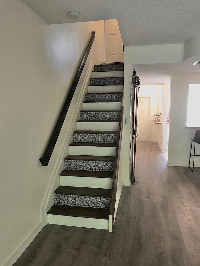 stairs featuring visible vents, a textured ceiling, baseboards, and wood finished floors