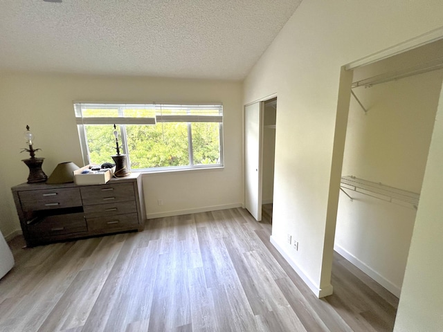 bedroom with light wood-type flooring, a closet, a textured ceiling, and baseboards