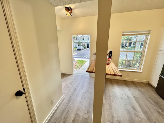 doorway featuring baseboards, a textured ceiling, and wood finished floors