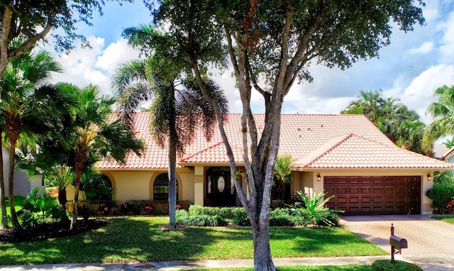 view of front of property featuring stucco siding, a front yard, an attached garage, and a tile roof