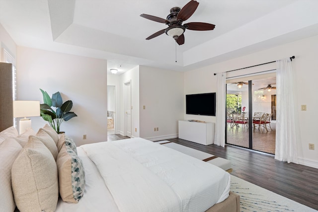 bedroom featuring a tray ceiling, access to outside, wood finished floors, and baseboards