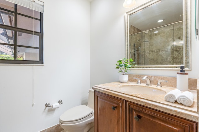 bathroom with tiled shower, toilet, and vanity