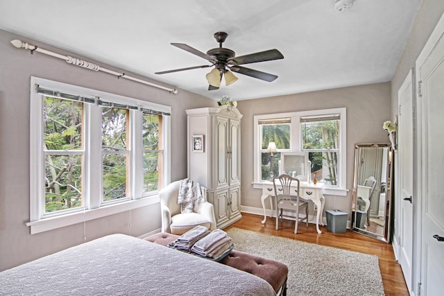 bedroom with multiple windows, a ceiling fan, and wood finished floors