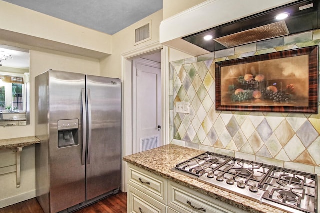 kitchen with stainless steel appliances, premium range hood, cream cabinetry, light stone countertops, and dark wood finished floors