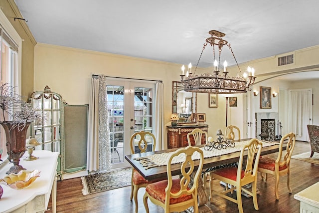 dining space featuring a fireplace, visible vents, wood finished floors, and french doors