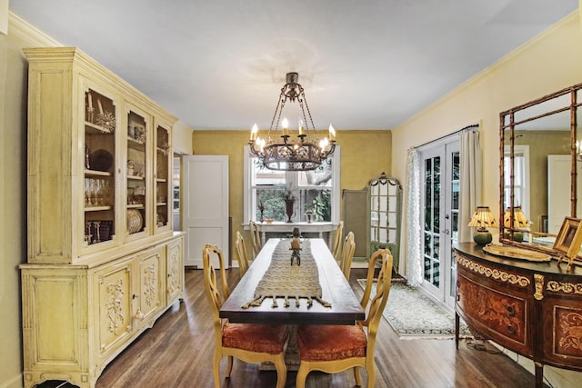 dining space featuring a notable chandelier, ornamental molding, dark wood-type flooring, and french doors