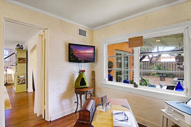 interior space featuring arched walkways, a textured wall, wood finished floors, visible vents, and ornamental molding