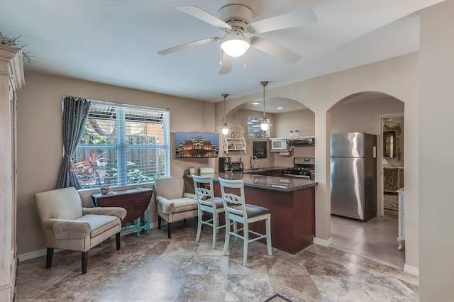 kitchen with arched walkways, appliances with stainless steel finishes, a sink, ventilation hood, and a peninsula