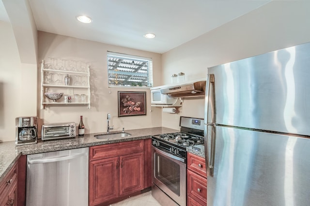 kitchen with recessed lighting, under cabinet range hood, a sink, appliances with stainless steel finishes, and dark stone countertops