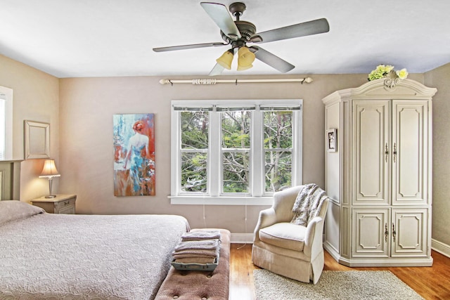 bedroom with light wood-type flooring, ceiling fan, and baseboards