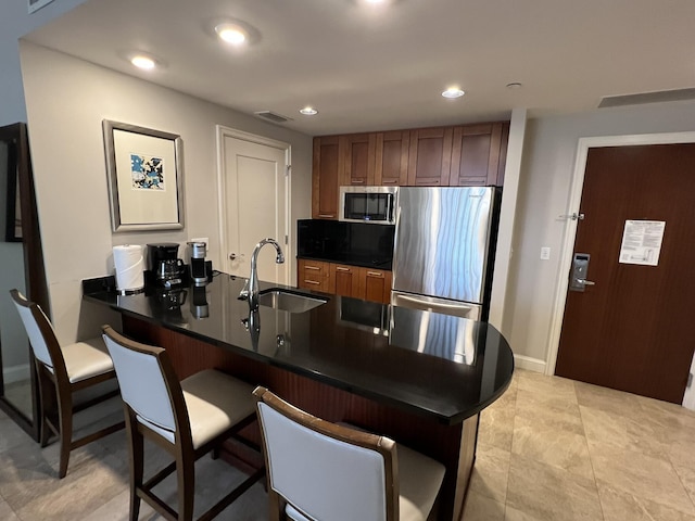 kitchen with visible vents, a peninsula, a sink, stainless steel appliances, and dark countertops