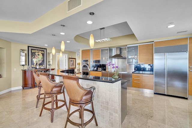 kitchen featuring visible vents, appliances with stainless steel finishes, wall chimney exhaust hood, modern cabinets, and a raised ceiling