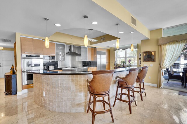 kitchen featuring appliances with stainless steel finishes, visible vents, wall chimney range hood, and modern cabinets