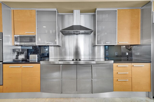 kitchen featuring wall chimney range hood, stainless steel microwave, modern cabinets, and backsplash