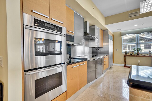 kitchen featuring decorative backsplash, appliances with stainless steel finishes, wall chimney range hood, modern cabinets, and baseboards