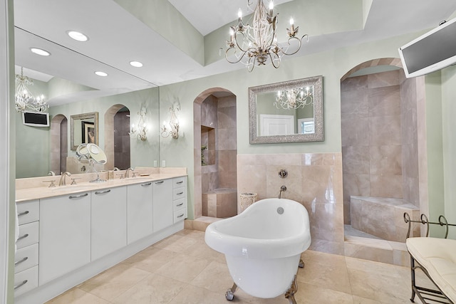 bathroom with a sink, a notable chandelier, tile walls, and a freestanding bath