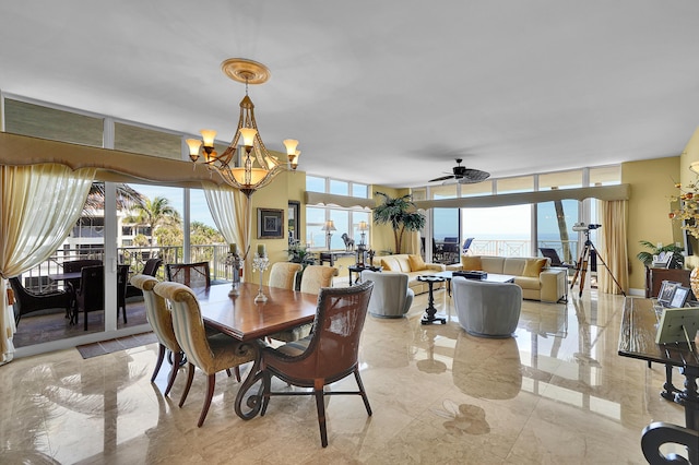 dining room featuring marble finish floor, expansive windows, and ceiling fan with notable chandelier