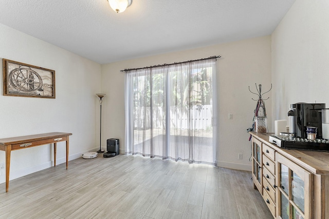 interior space with a textured ceiling, baseboards, and wood finish floors