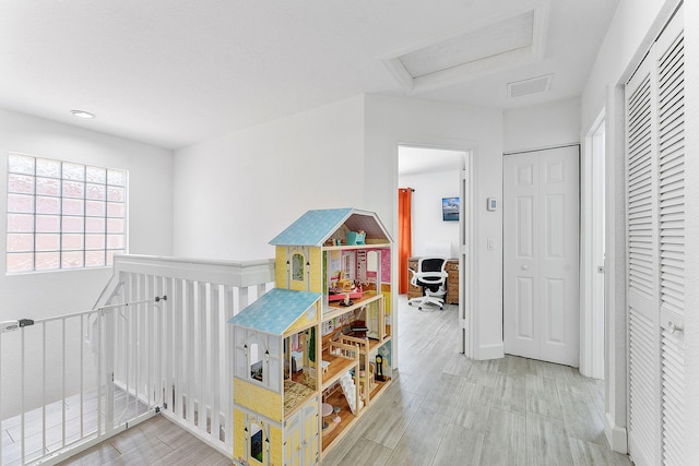 hall featuring visible vents, attic access, and wood tiled floor