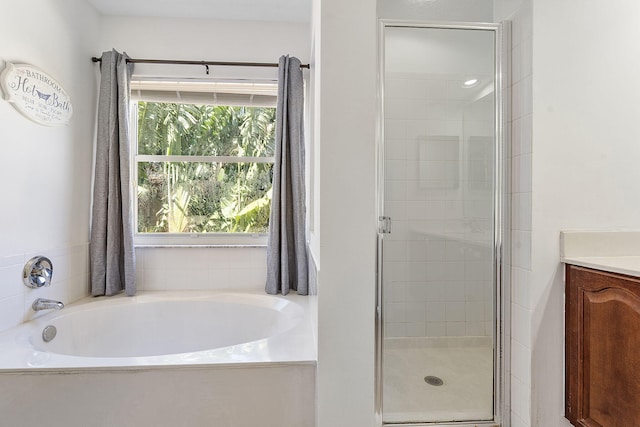 bathroom featuring a stall shower, vanity, and a garden tub