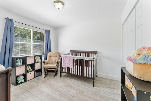 bedroom with a crib, baseboards, and wood tiled floor