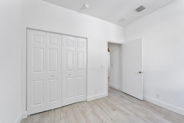 unfurnished bedroom with visible vents, a closet, and wood tiled floor