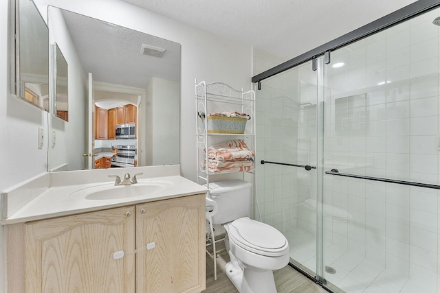 full bathroom with vanity, a shower stall, toilet, and visible vents