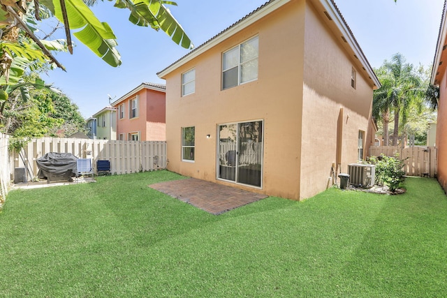 rear view of property featuring cooling unit, a lawn, a fenced backyard, and stucco siding