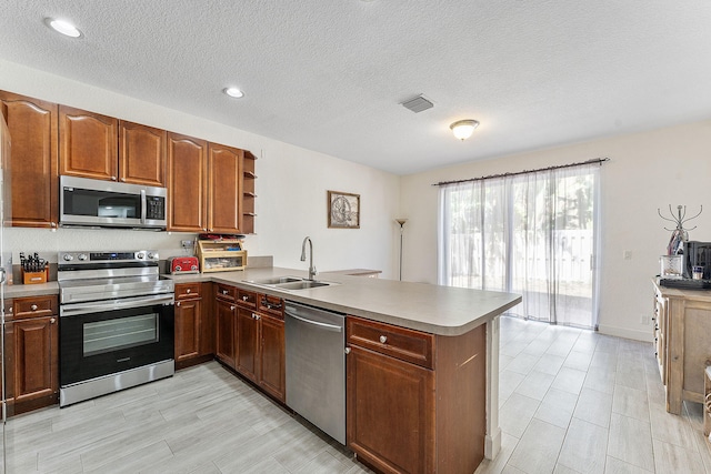 kitchen featuring visible vents, a peninsula, open shelves, a sink, and appliances with stainless steel finishes