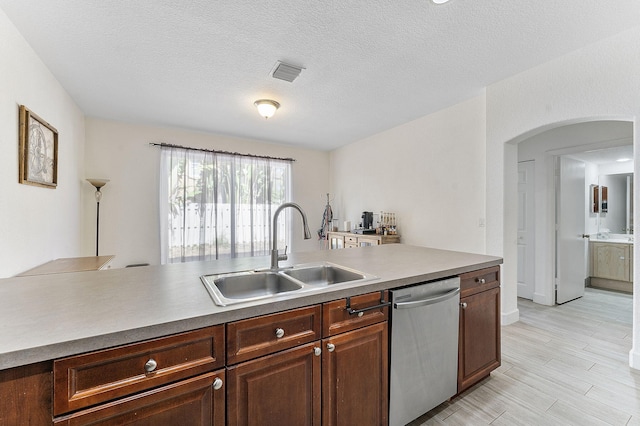 kitchen featuring visible vents, dishwasher, arched walkways, a textured ceiling, and a sink