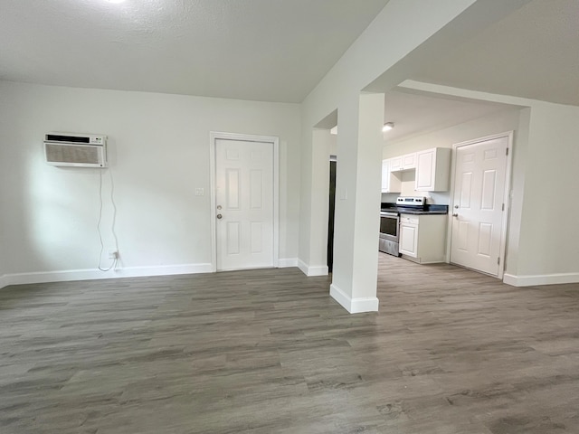 interior space with a wall unit AC, baseboards, and wood finished floors