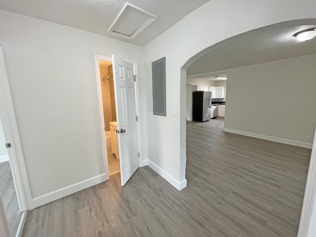 corridor featuring attic access, arched walkways, baseboards, and wood finished floors