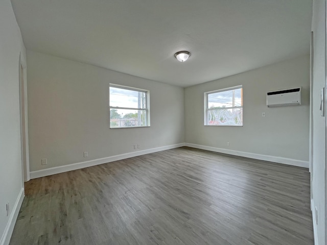 spare room featuring baseboards, wood finished floors, and a wall mounted AC