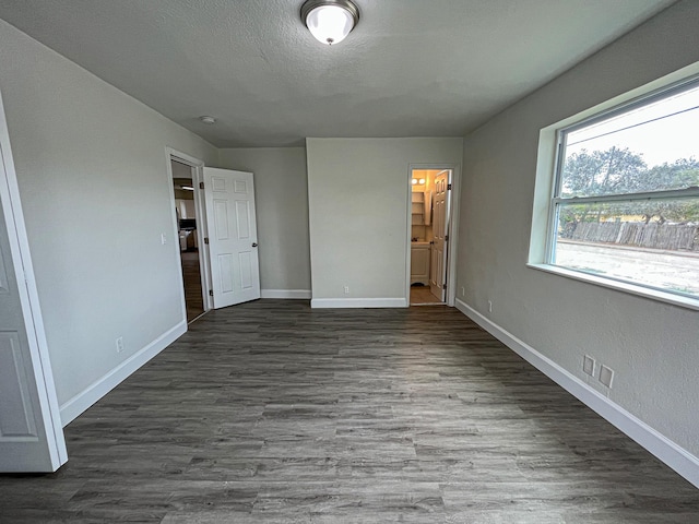 unfurnished bedroom featuring a textured ceiling, dark wood finished floors, connected bathroom, and baseboards