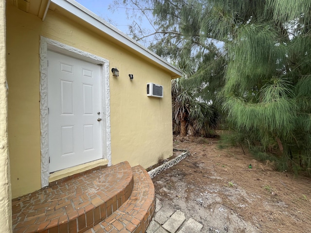 view of exterior entry featuring a wall mounted AC and stucco siding