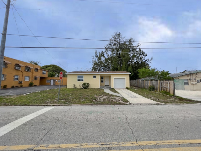 view of front of home with an attached garage, fence, concrete driveway, stucco siding, and a front lawn