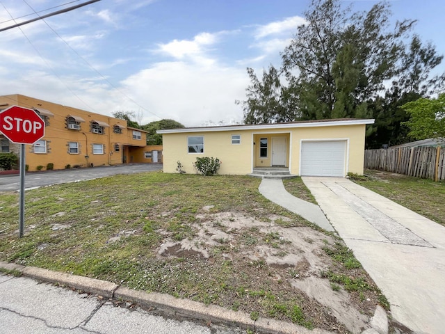 view of front of house featuring driveway, an attached garage, fence, and stucco siding