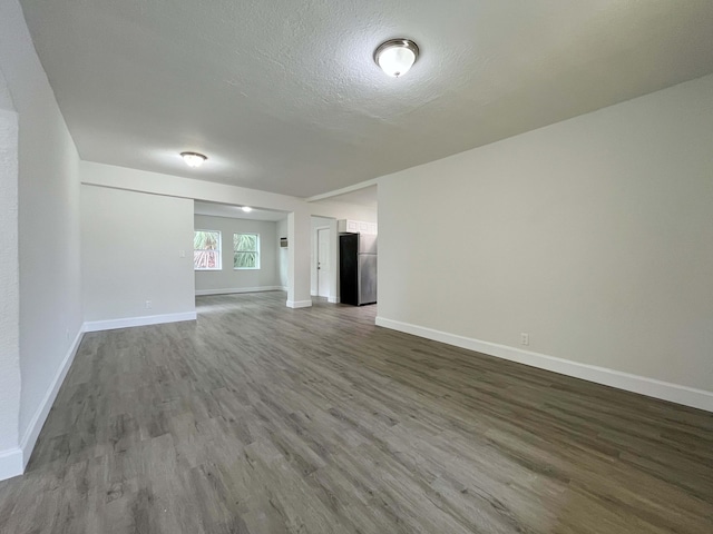 unfurnished room with dark wood-style floors, baseboards, and a textured ceiling