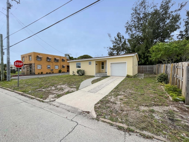 view of front facade with a garage, concrete driveway, fence, and stucco siding