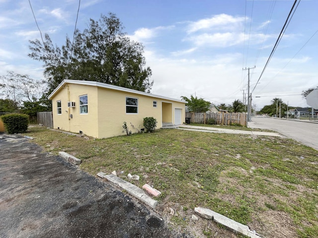 view of front facade with driveway, a front lawn, fence, and stucco siding